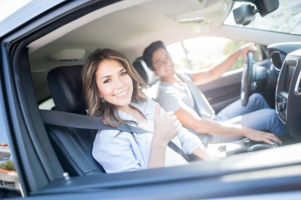 Happy couple going on a road trip and showing thumbs up